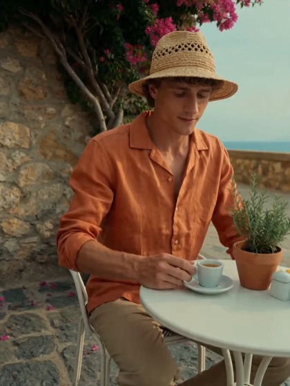 A man at a café table in the sun